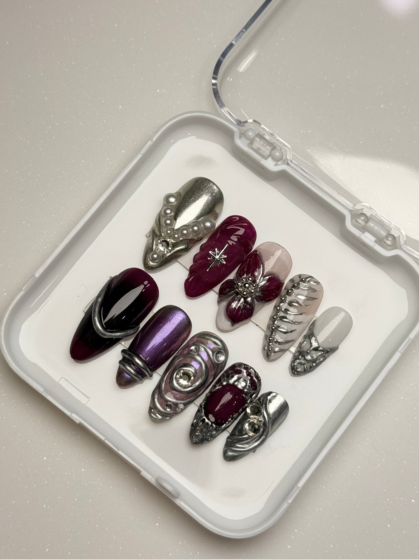 Set of decorative nails in various colors on a white tray with a mirror chrome nail set 3D flower nail set purple nail set