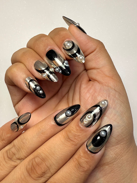 Hand with black and silver nail art on a plain background silver chrome nail set abstract nail set