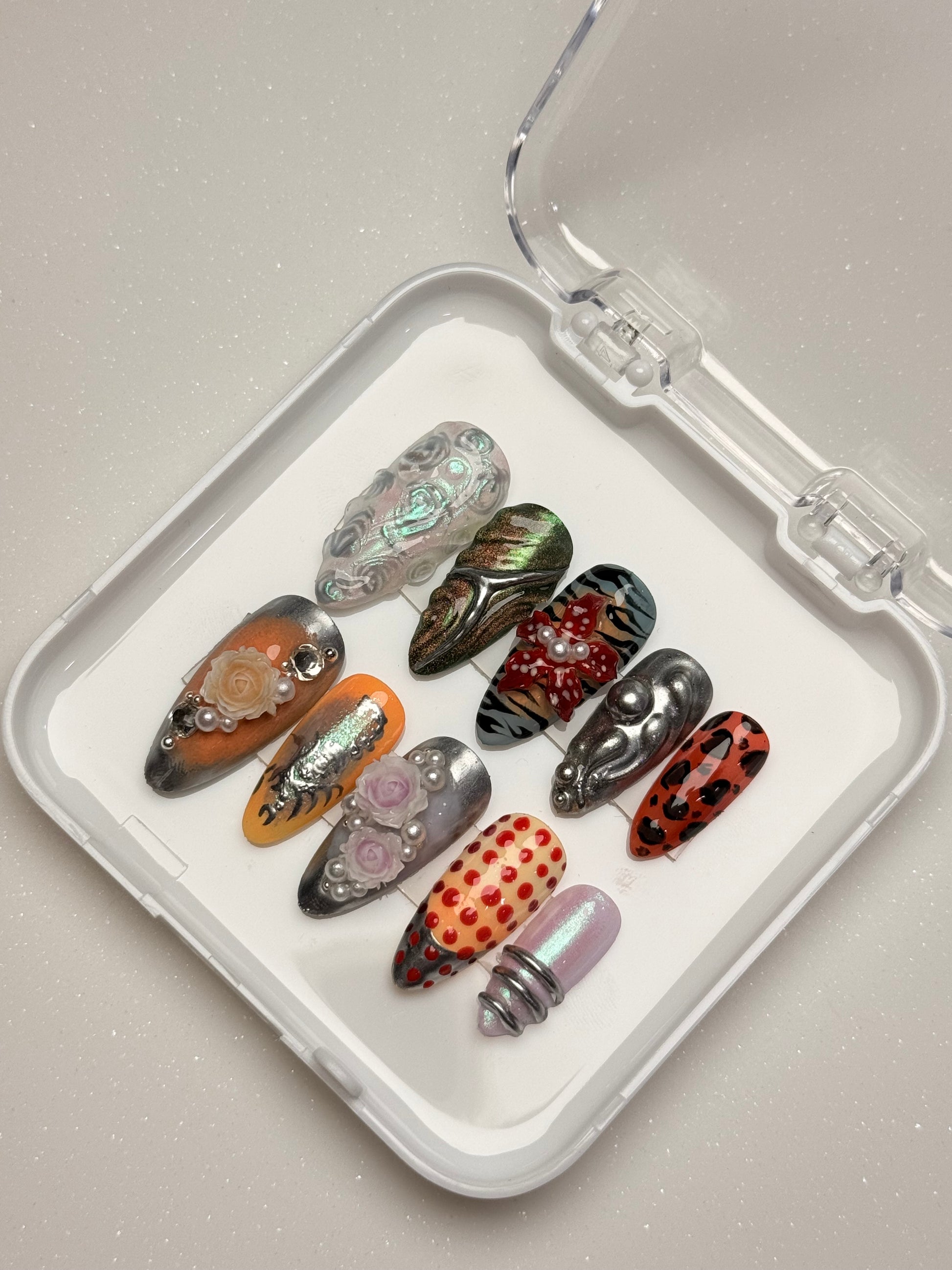 Set of decorative false nails in various designs on a clear tray nail art luxury press-on nail set chrome 3D flower nail set, pearl nails