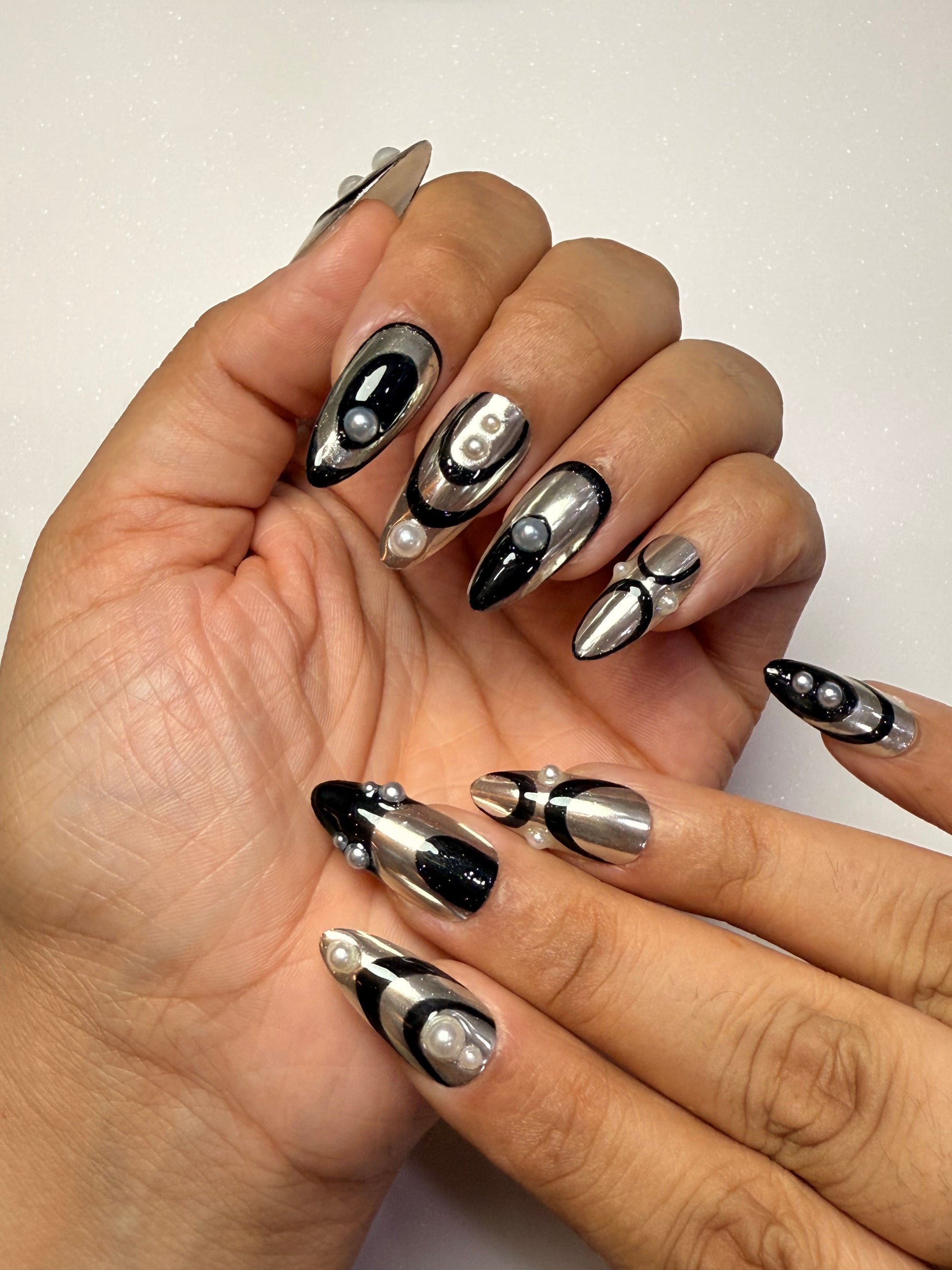 Close-up of hands with black and silver nail art on a neutral background silver chrome nail set abstract nail set 