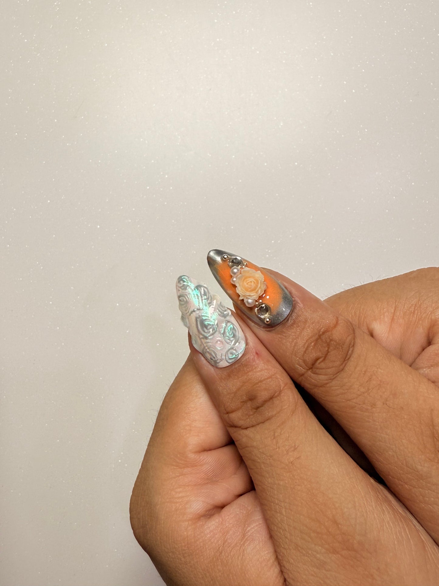 Close-up of a hand with intricately designed nails on a light background nail art luxury press-on nail set chrome 3D flower nail set, pearl nails