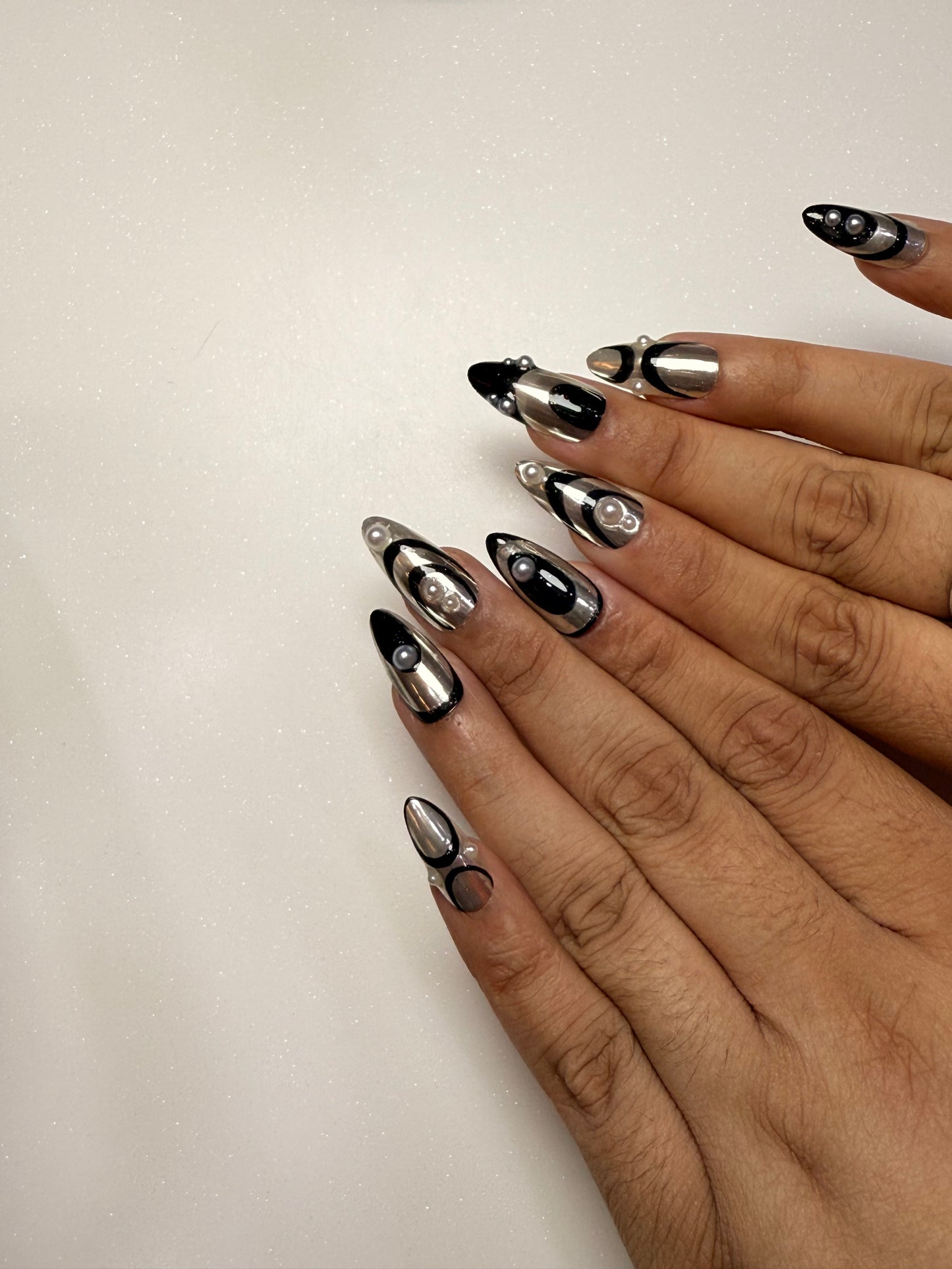 Close-up of a hand with metallic nail art on a plain background silver chrome nail set abstract nail set 