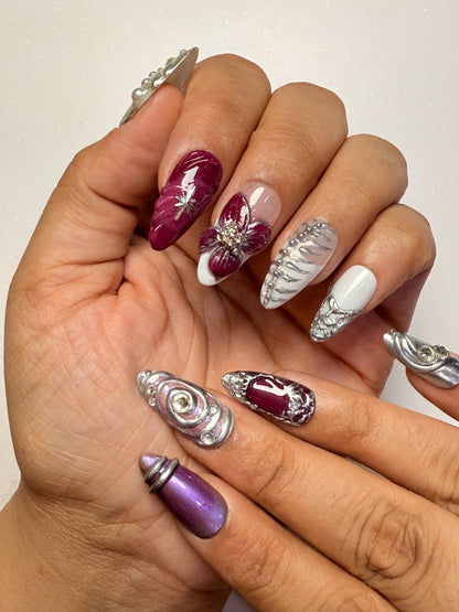 Close-up of hands with decorative nail art featuring purple, silver, and white designs chrome nail set 3D flower nail set  purple nail set