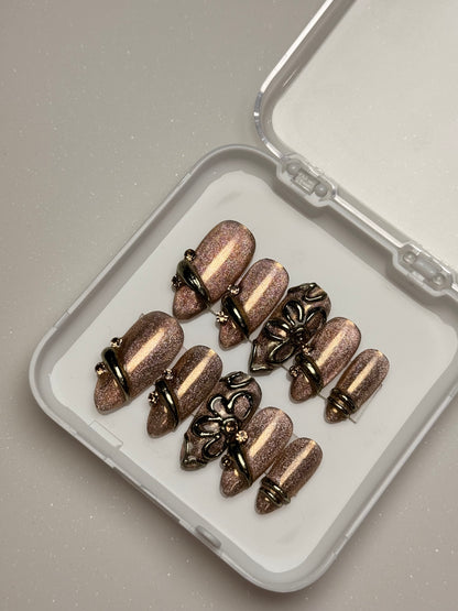 Bronze-colored fishing lures on a white tray with a clear lid brown cat eye press on nail set  3D nail set chrome nail set