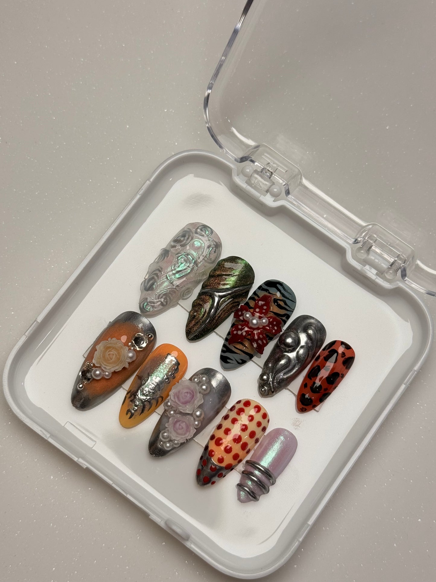 Set of decorative nails in a clear case on a light gray background nail art luxury press-on nail set chrome 3D flower nail set, pearl nails