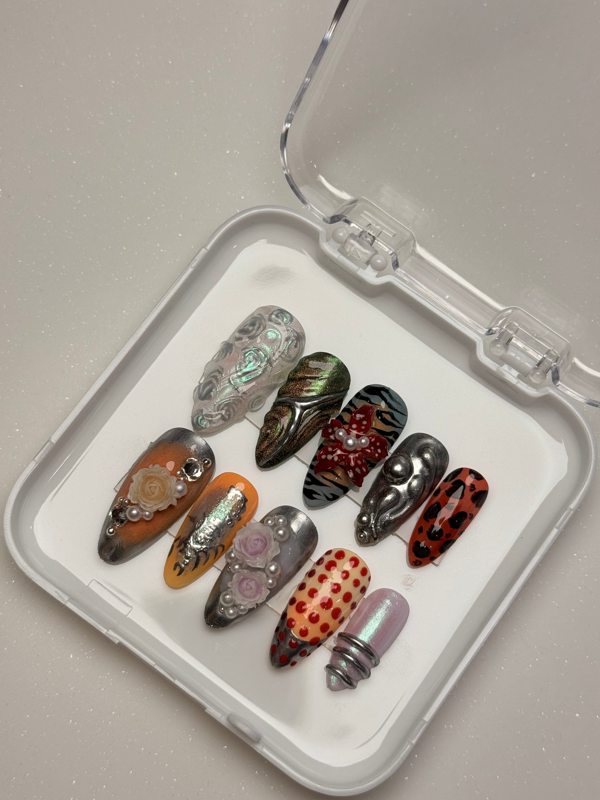 Set of decorative nails in a clear case on a light gray background nail art luxury press-on nail set chrome 3D flower nail set, pearl nails