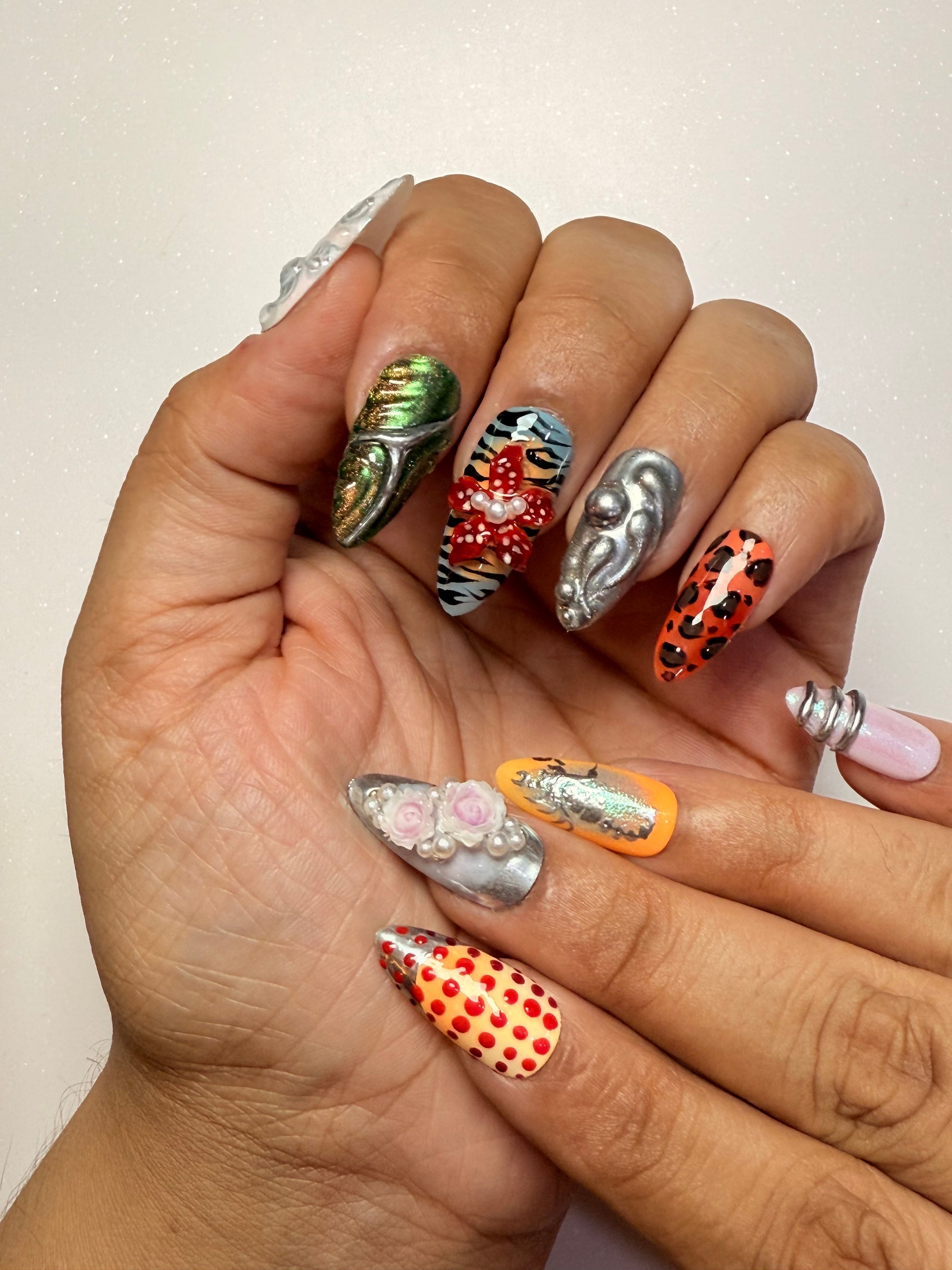 Hand with intricately designed nails featuring various patterns and colors nail art luxury press-on nail set chrome 3D flower nail set, pearl nails