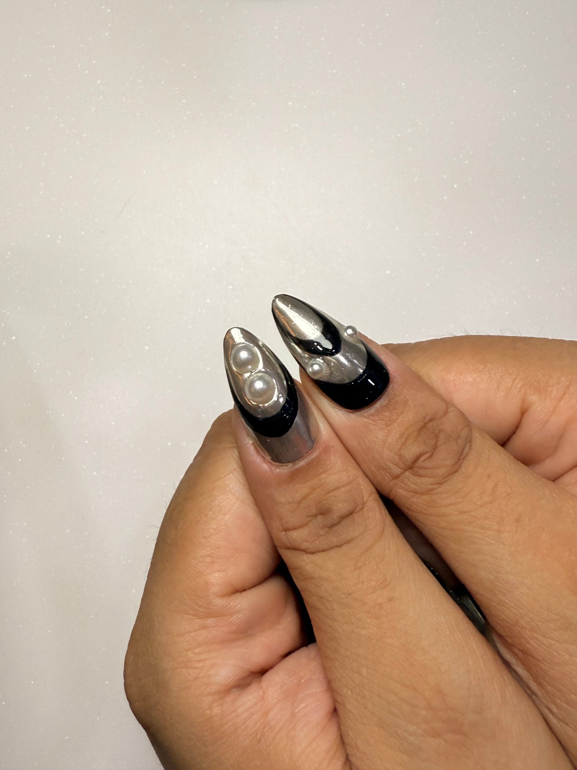 Close-up of a hand with decorative nail art on a plain background silver chrome nail set abstract nail set 
