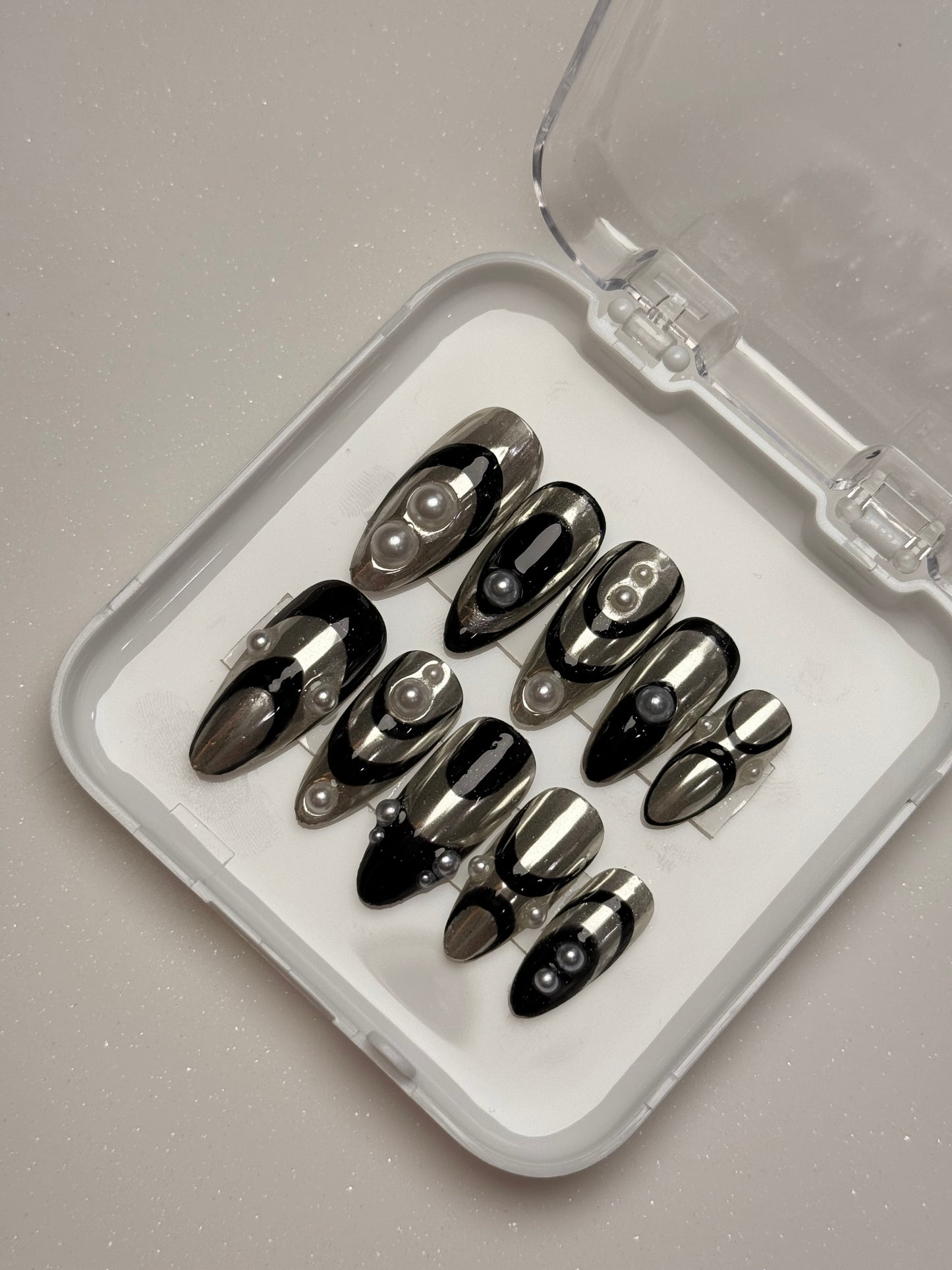 Set of black nail tips in a clear case on a gray background silver chrome nail set abstract nail set 