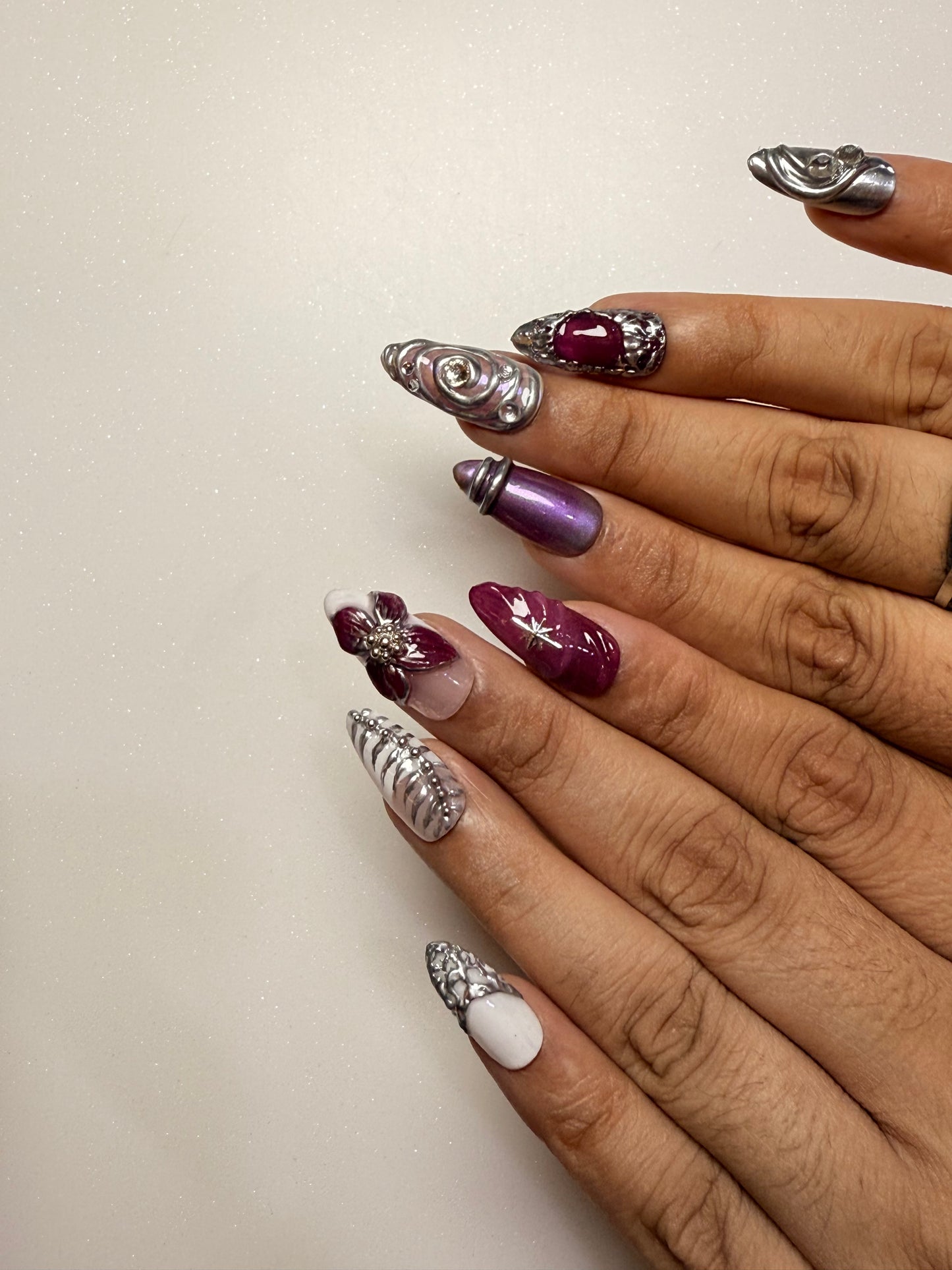 Close-up of hands with decorative nail art on a neutral background chrome nail set 3D flower nail set  purple nail set