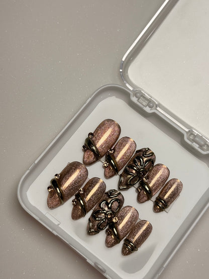 Bronze-colored fishing lures in a clear container on a light gray background brown cat eye press on nail set  3D nail set chrome nail set