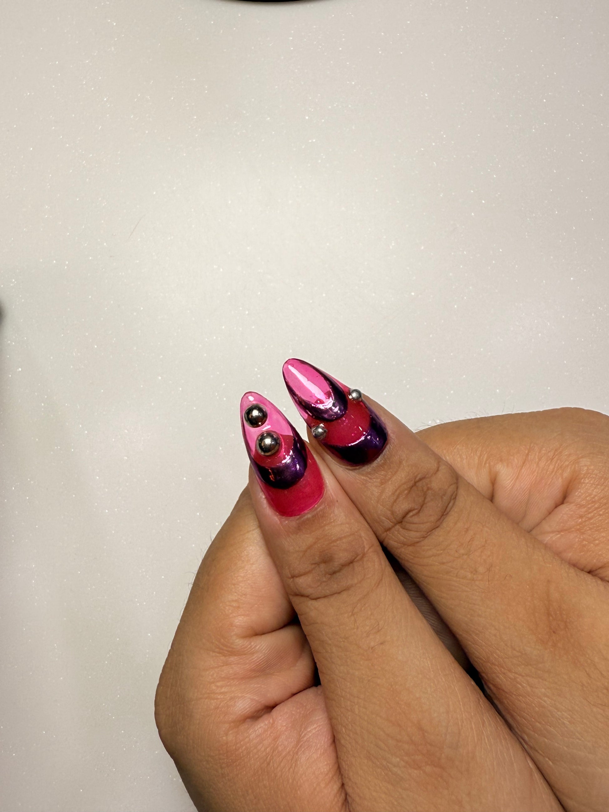 Close-up of a hand with pink and purple nail polish on a plain background pink chrome nail set abstract nail set 