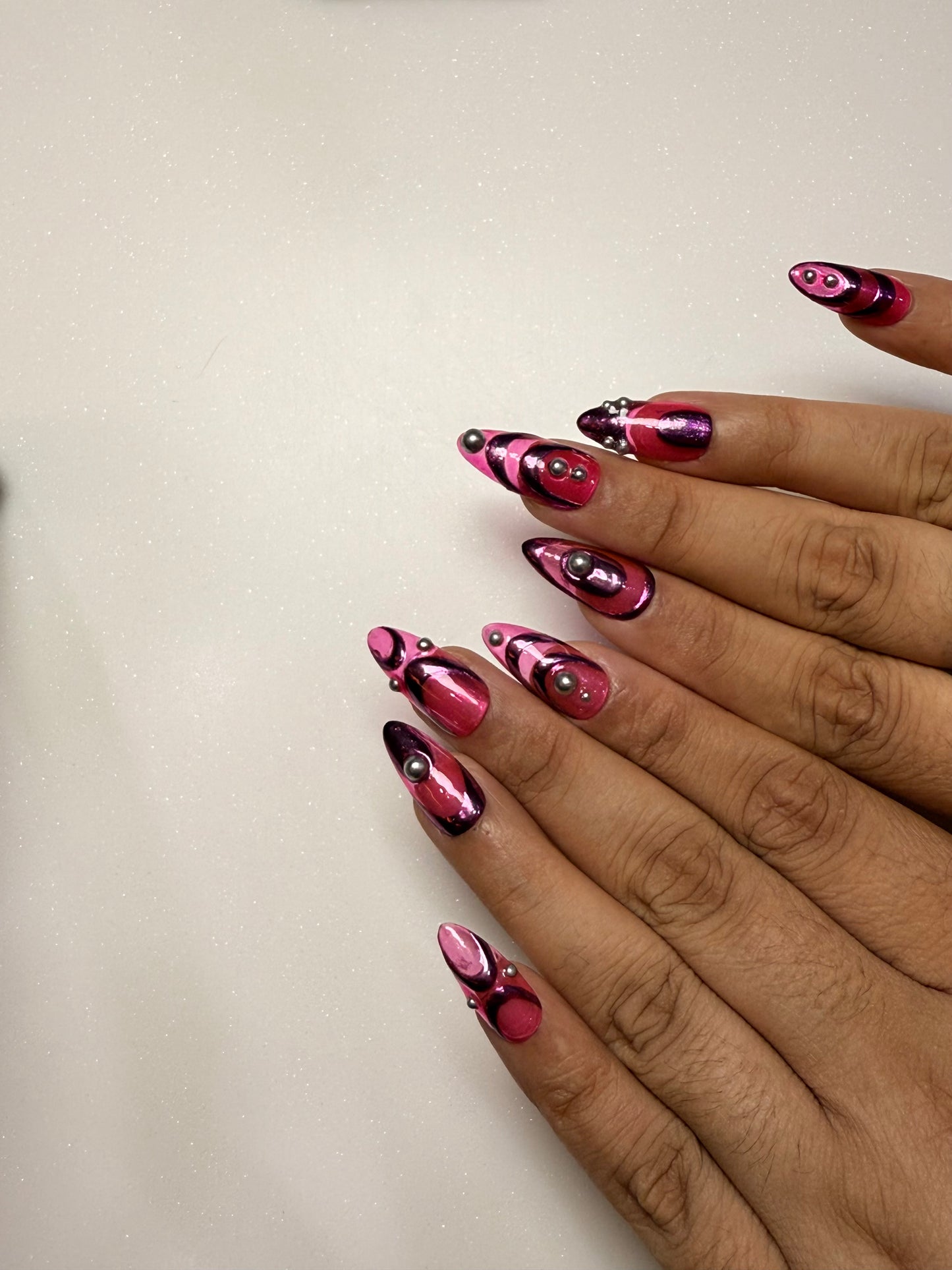 Hand with pink and black nail design on a plain background pink chrome nail set abstract nail set 