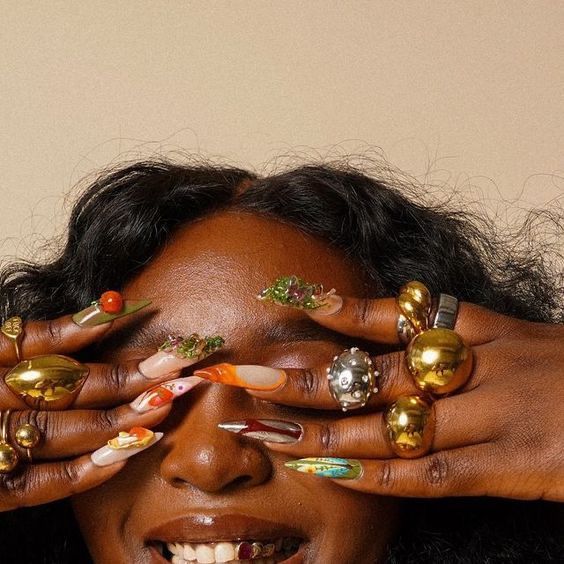 Maximalist 3D nail art in citrus, green and gold worn with mirror-polished statement rings held over the eyes